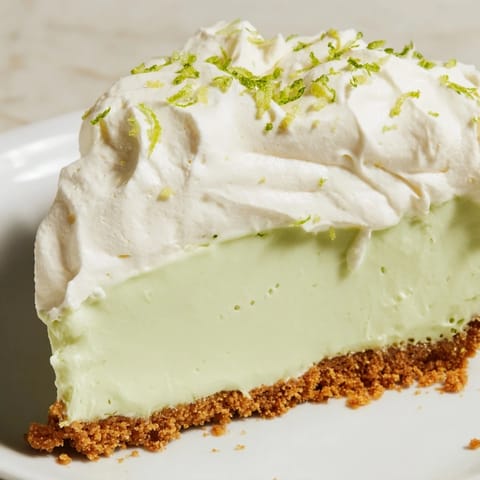 Whipped cream topping on a chilled Key Lime Pie slice, garnished with lime zest for extra zest.