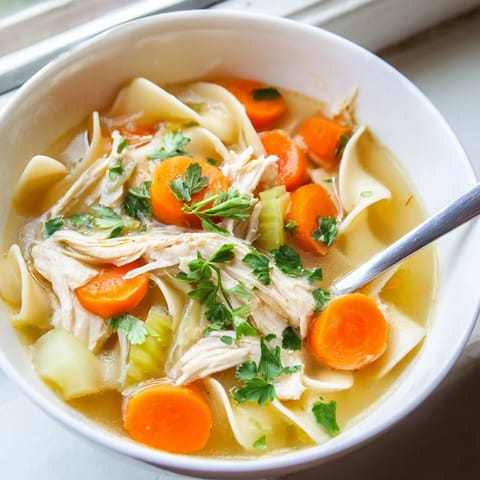 Cozy pot of classic Chicken Noodle Soup simmers with fresh vegetables and herbs, ready for a comforting lunch.