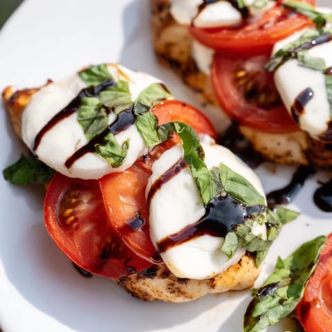 Golden seared Caprese Chicken Skillet with melted mozzarella, ripe tomato slices, and fresh basil leaves, drizzled with balsamic glaze.  