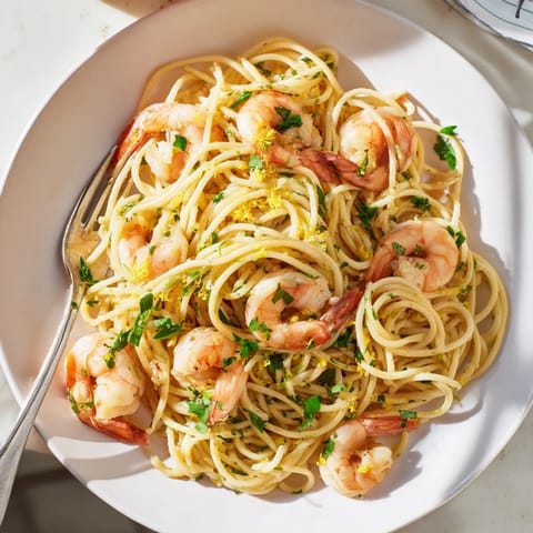 A steaming bowl of Lemon Garlic Shrimp Pasta showcases fresh parsley garnish and vibrant lemon zest.  