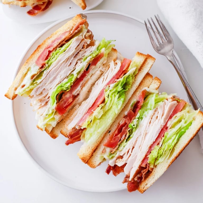 Fresh lettuce leaves and ripe tomato slices add vibrant color to this hearty turkey club sandwich served on a rustic wooden cutting board.