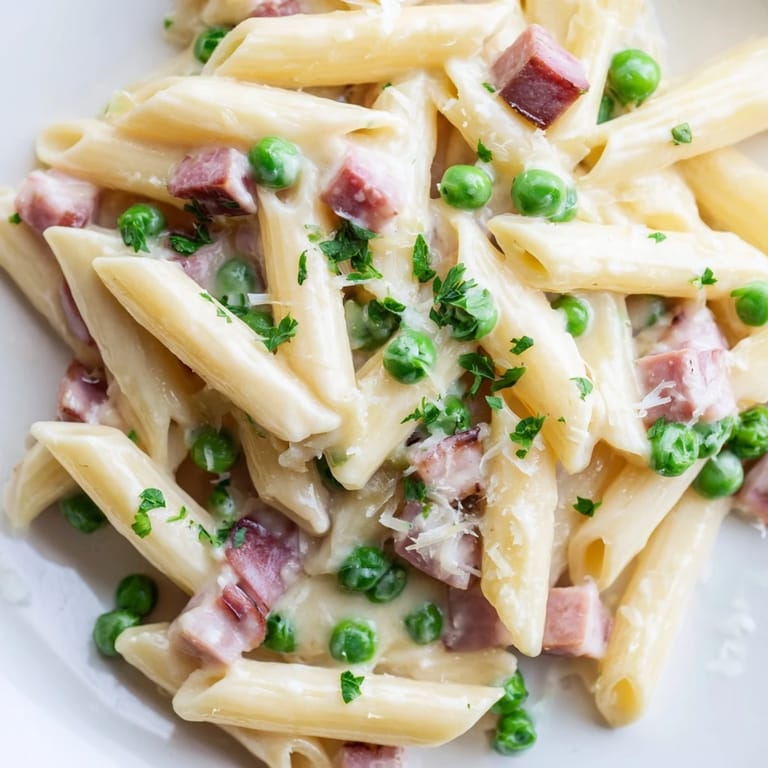 Savory Spring Pea & Ham Pasta served in a white bowl, garnished with fresh parsley and grated Parmesan, perfect for a cozy March dinner.