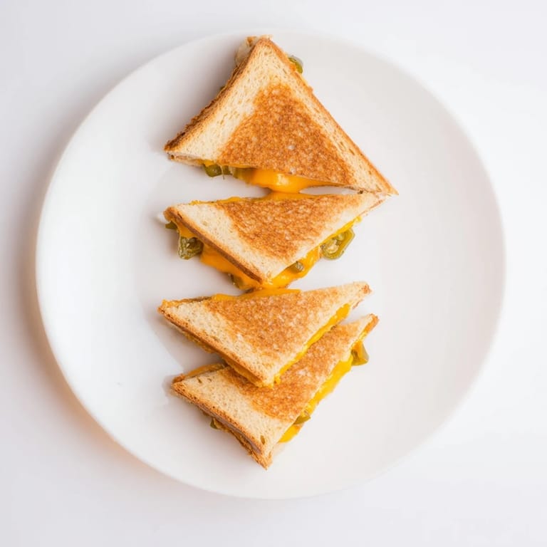 Crusty grilled bread encasing spicy pepper jack and pickled jalapeños, cut diagonally to reveal the melted filling.