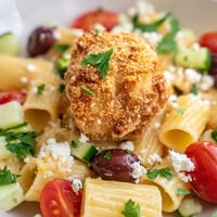 Golden crispy chicken bites nestled on top of penne pasta tossed with fresh cucumber, tomatoes, olives, and crumbled feta cheese.