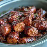 Crock Pot BBQ Cocktail Sausage simmering in a sticky apricot glaze inside a slow cooker.